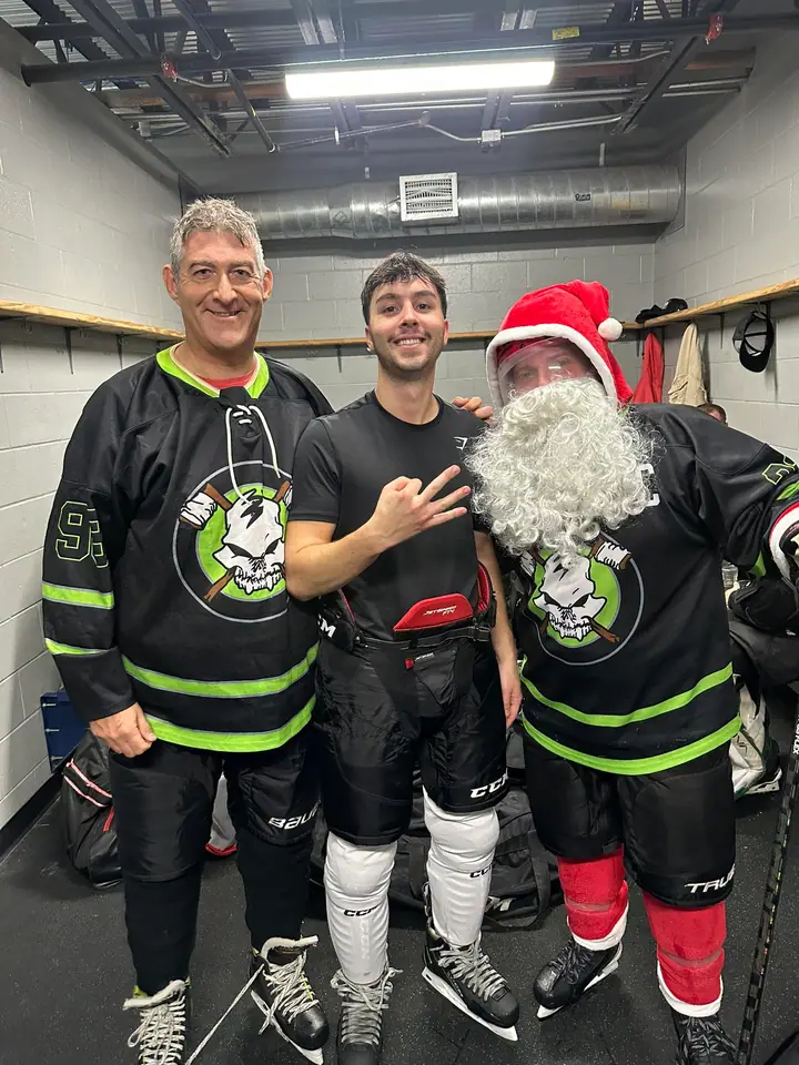 Two Stick N Bones players in the locker room with Santa in full gear