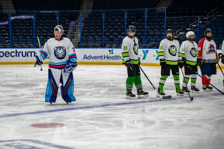 A goalie and skaters taking the ice at the arena